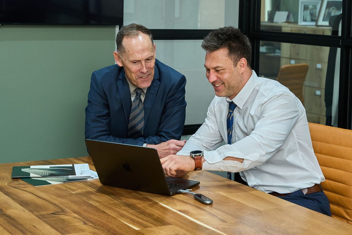 Two XPert Wealth advisers reviewing a client portfolio together on a laptop in the boardroom